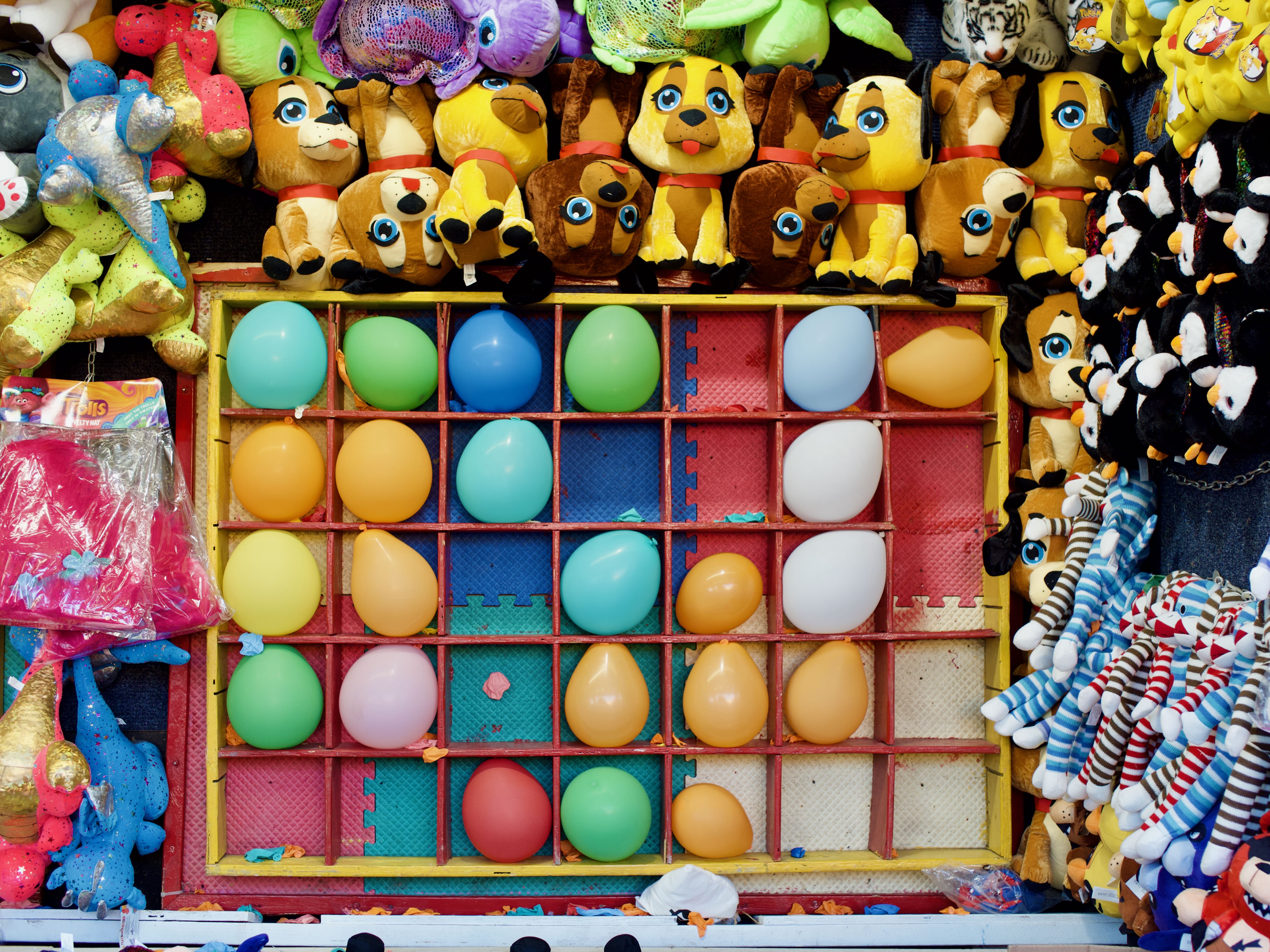 A photograph of multicolored balloons at a small fair.